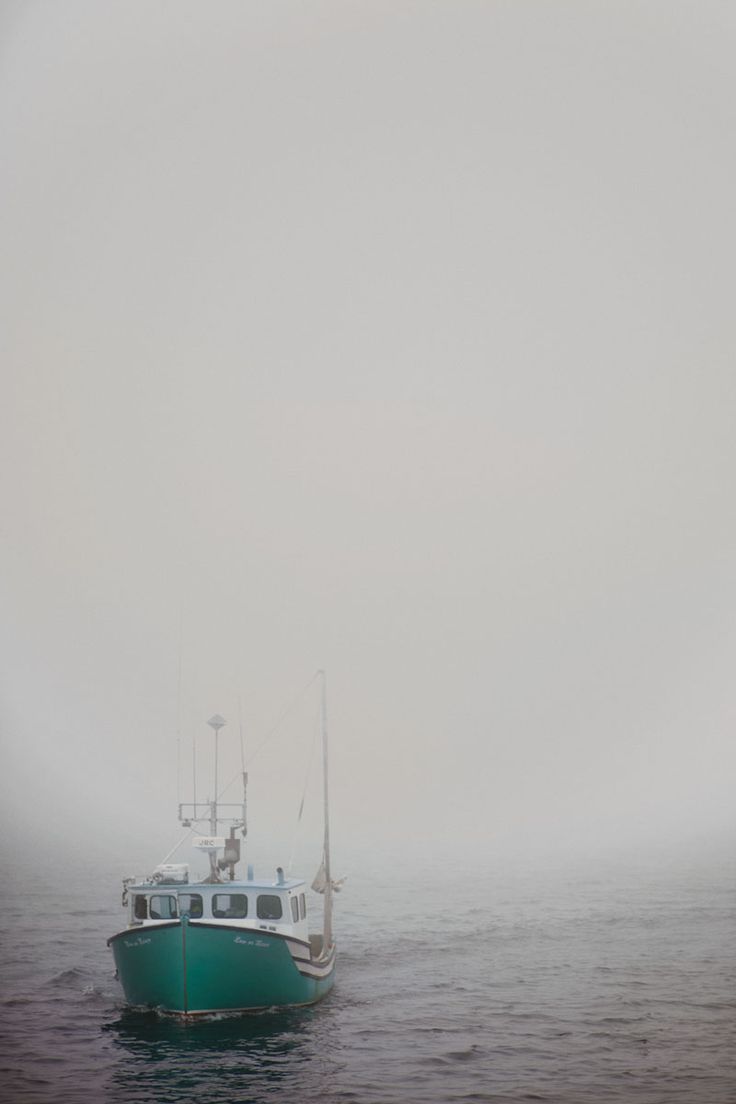 A lobster boat chugs slowly towards the camera through thick fog