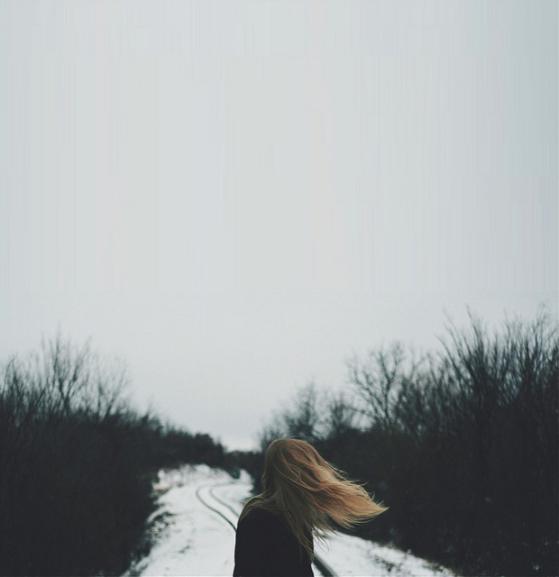 A woman looks back at a snowy path as the wind blows her hair